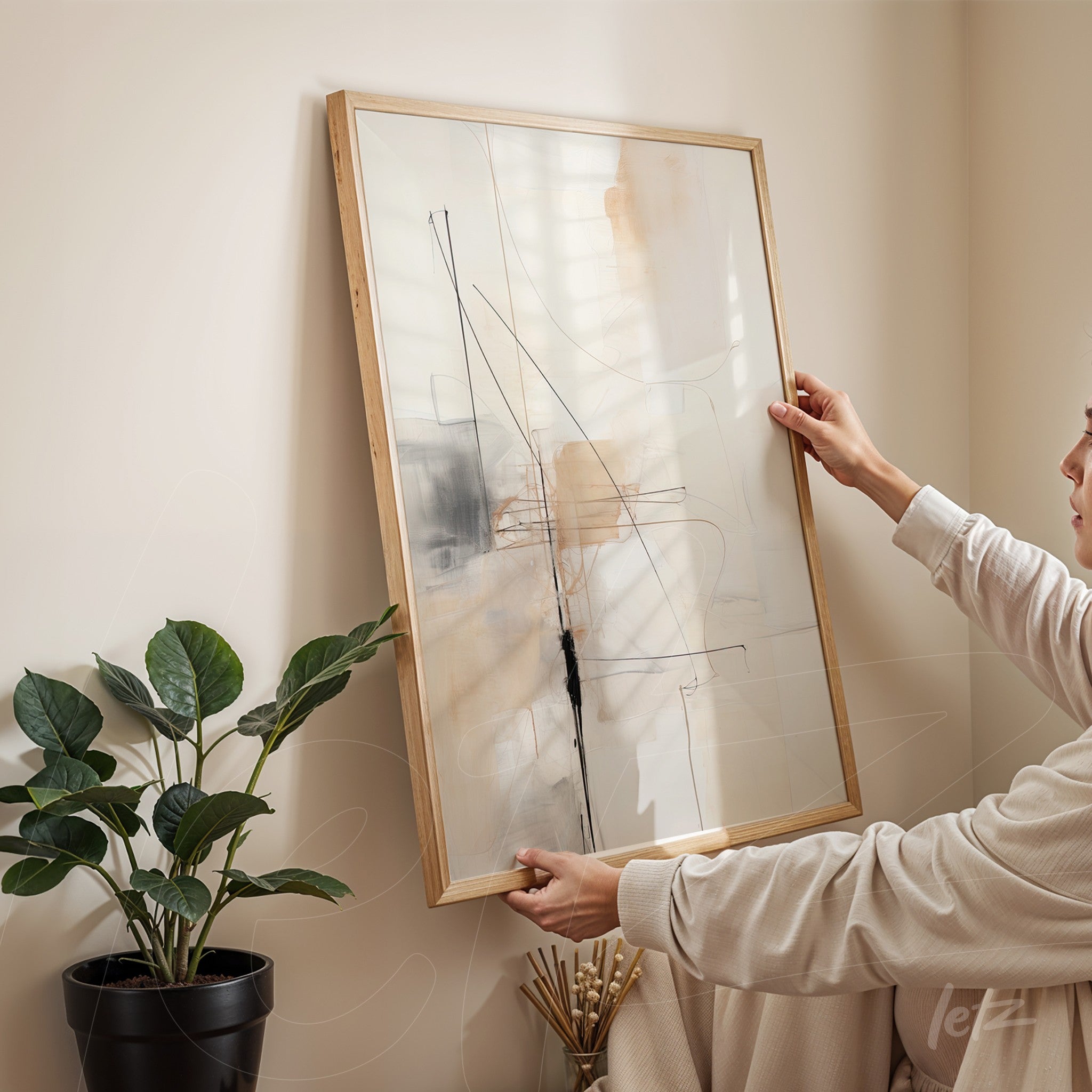 quadro abstrato em moldura de madeira clara com linhas e formas sutis em tons neutros, segurado por pessoa ao lado de planta verde