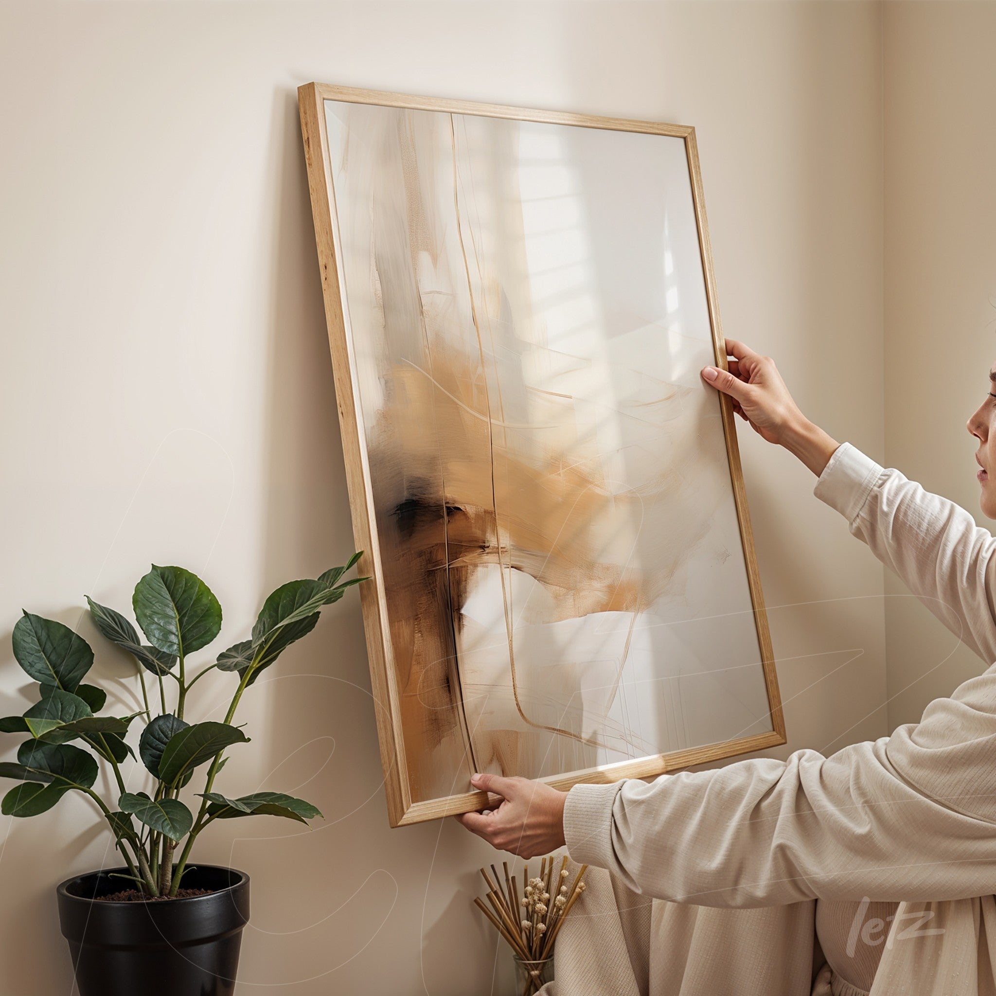 quadro com arte abstrata em tons terrosos com moldura em madeira clara, sendo segurado por uma pessoa em ambiente minimalista