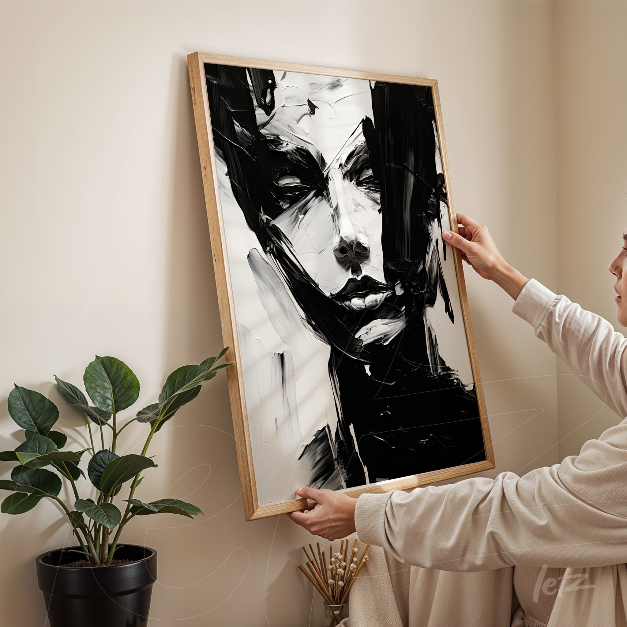 quadro abstrato em preto e branco apresentando uma figura humana em uma moldura de madeira natural, exibido em ambiente minimalista com planta ao fundo