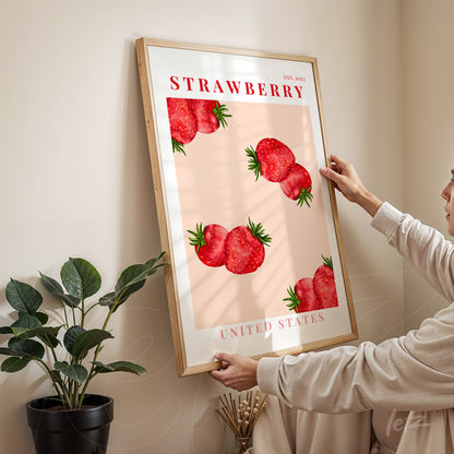 quadro com arte de morangos em fundo rosa e moldura de madeira clara