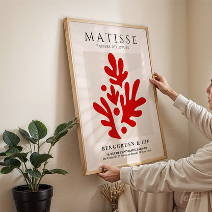 quadro com arte de Matisse em moldura de madeira clara, retratando formas orgânicas vermelhas em fundo branco