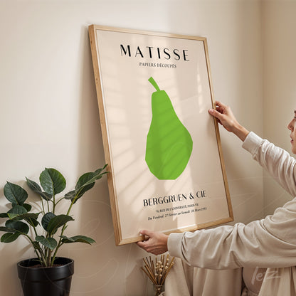 quadro em moldura de madeira clara com arte inspirada em Matisse, destacando uma pera verde em fundo claro