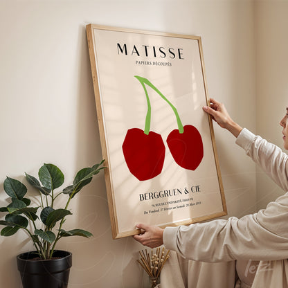 quadro com arte de Matisse apresentando duas cerejas vermelhas em fundo claro e moldura de madeira clara