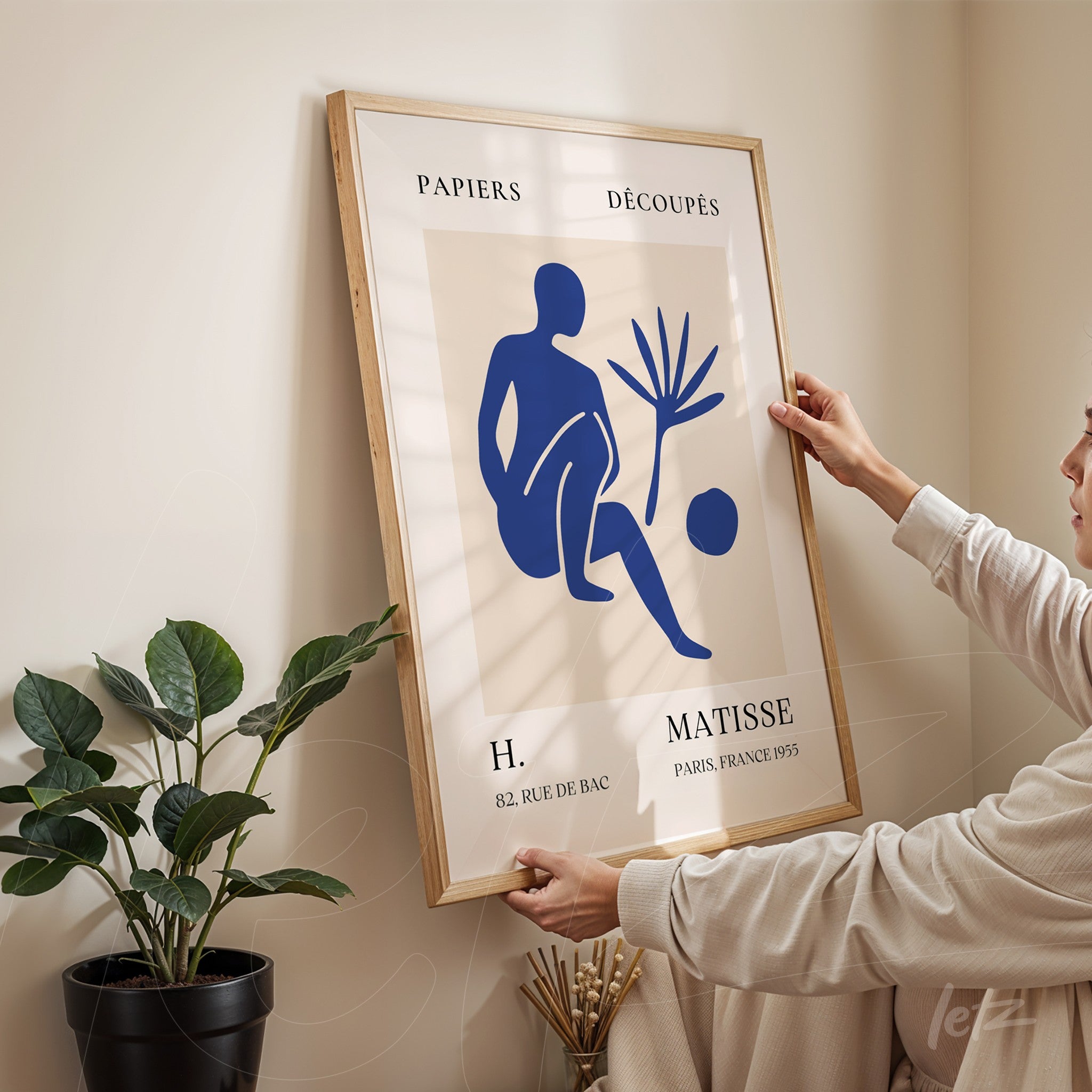 quadro com arte de figura estilizada em azul sobre fundo claro, moldura de madeira clara