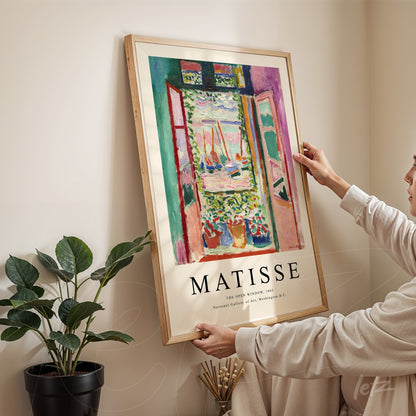 quadro com arte de Matisse retratando uma janela aberta com vista para um jardim, moldurado em madeira clara