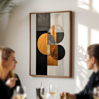quadro com arte abstrata em tons de preto, laranja e cinza, moldura de madeira clara exibido em parede branca com pessoas ao fundo