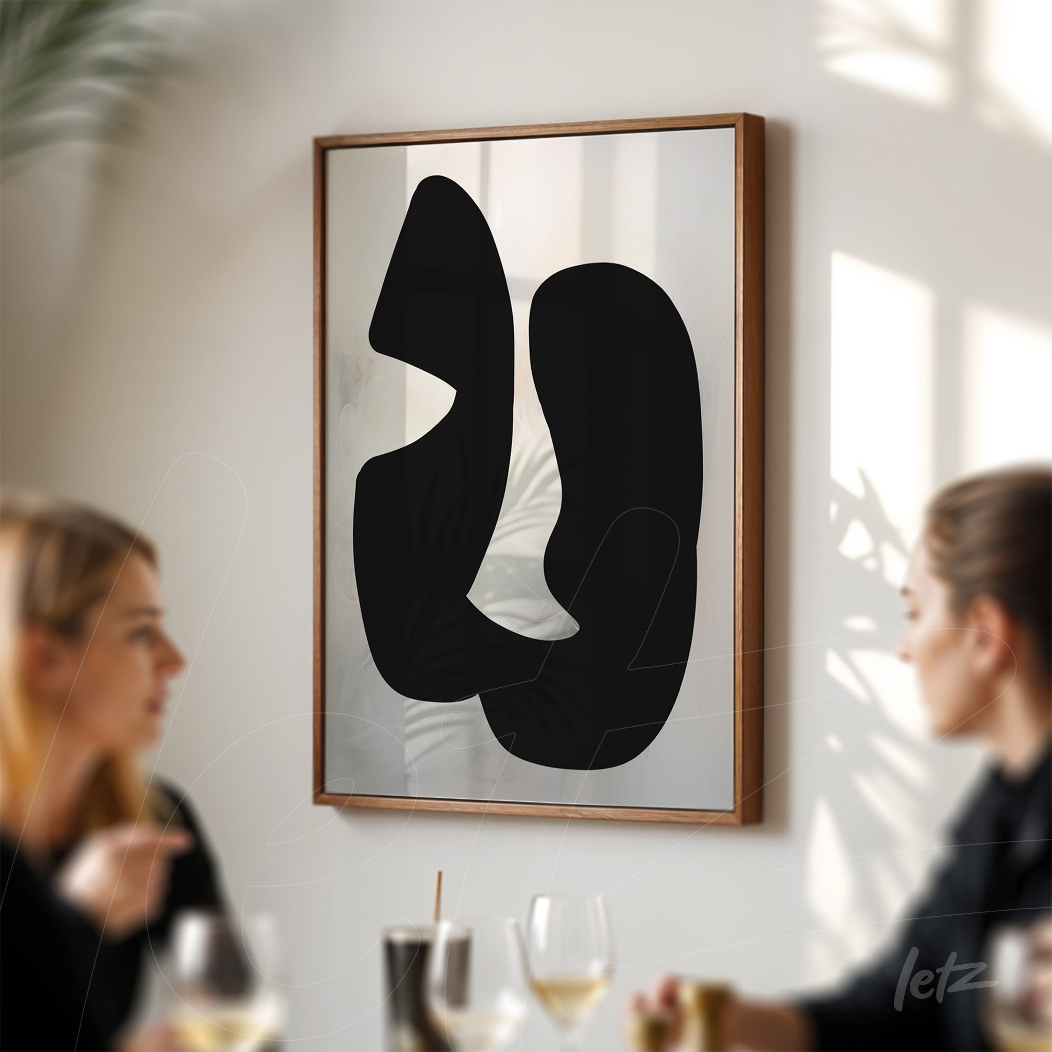 quadro com arte abstrata em preto sobre fundo claro, decorado com moldura de madeira clara, exibido em ambiente com iluminação natural