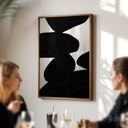 quadro com arte abstrata em preto e branco, exibido em moldura de madeira sobre parede clara, com dois espectadores em ambiente de restaurante