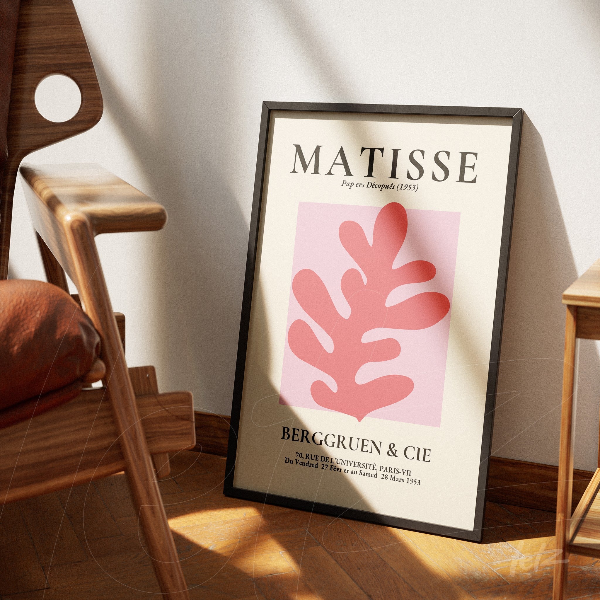 quadro decorativo em moldura preta com ilustração minimalista em tons de rosa de folhas, apoiado em cadeira de madeira