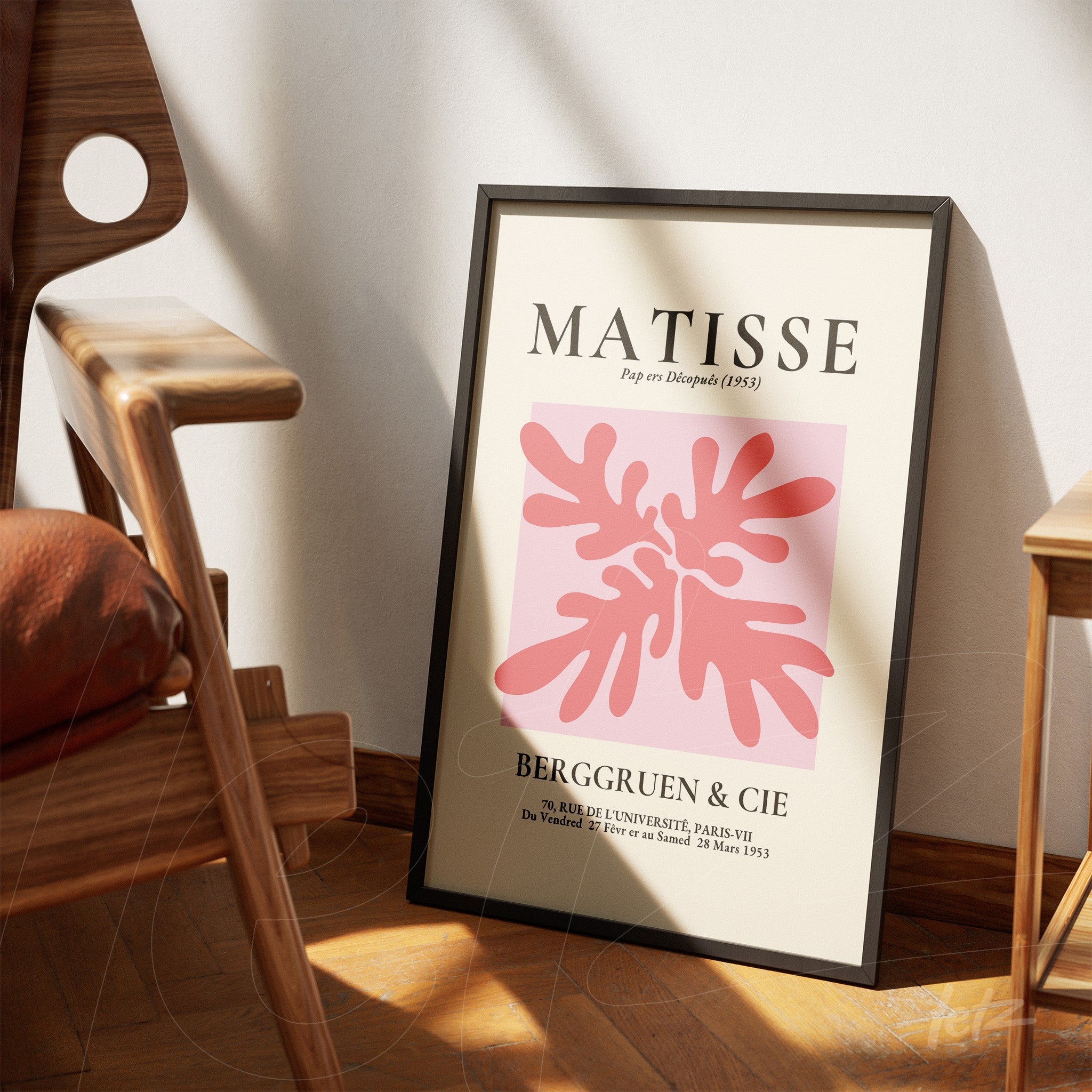 quadro com arte moderna de formas fluidas em tons de rosa, com moldura preta, apoiado em um chão de madeira