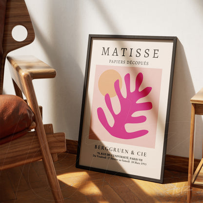 quadro com arte moderna composta por formas abstratas em rosa e laranja, moldura preta fina, apoiado em cadeira de madeira