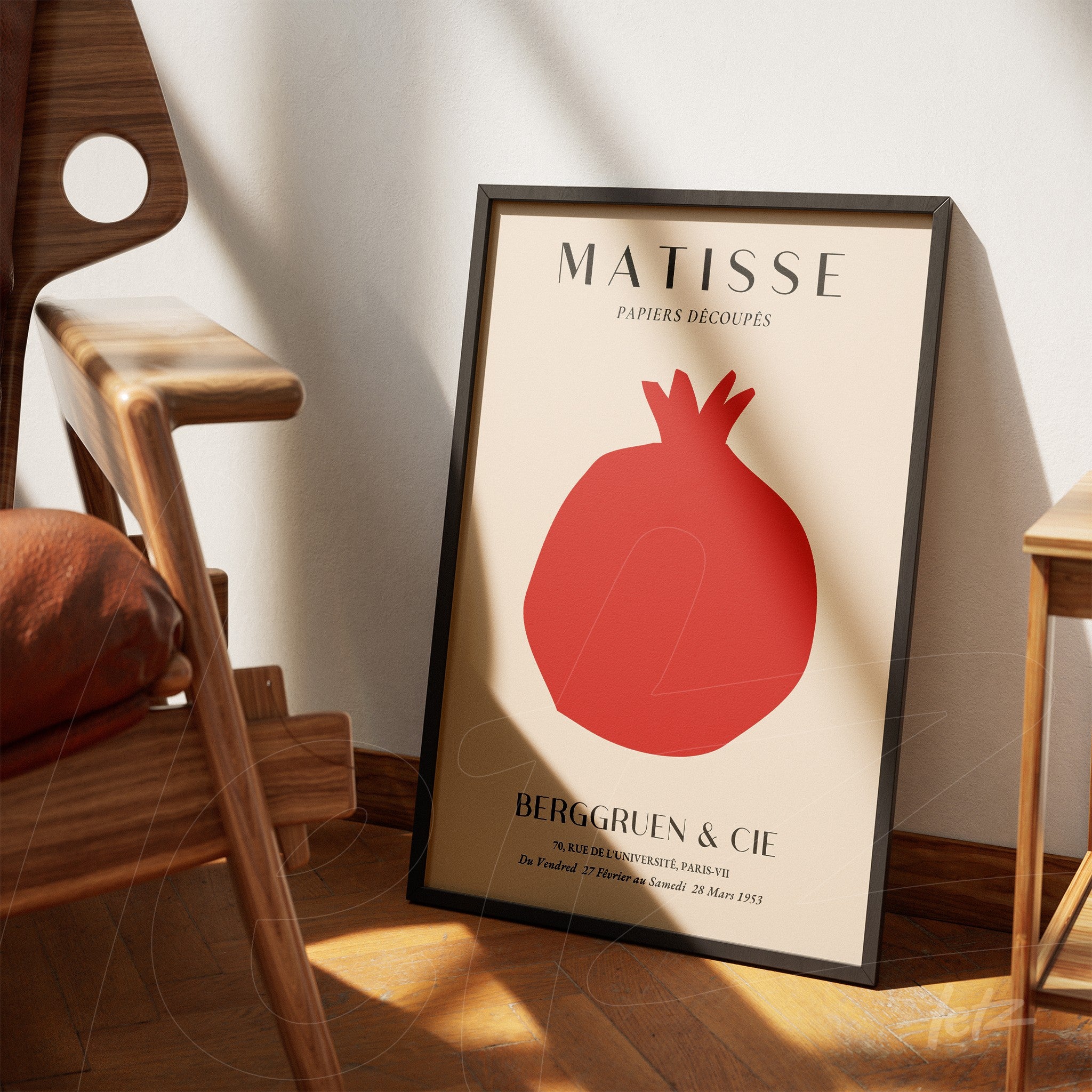 quadro decorativo com arte de Matisse, apresentando uma silhueta vermelha de romã em fundo claro, emoldurado com moldura preta fina, apoiado ao lado de uma cadeira de madeira