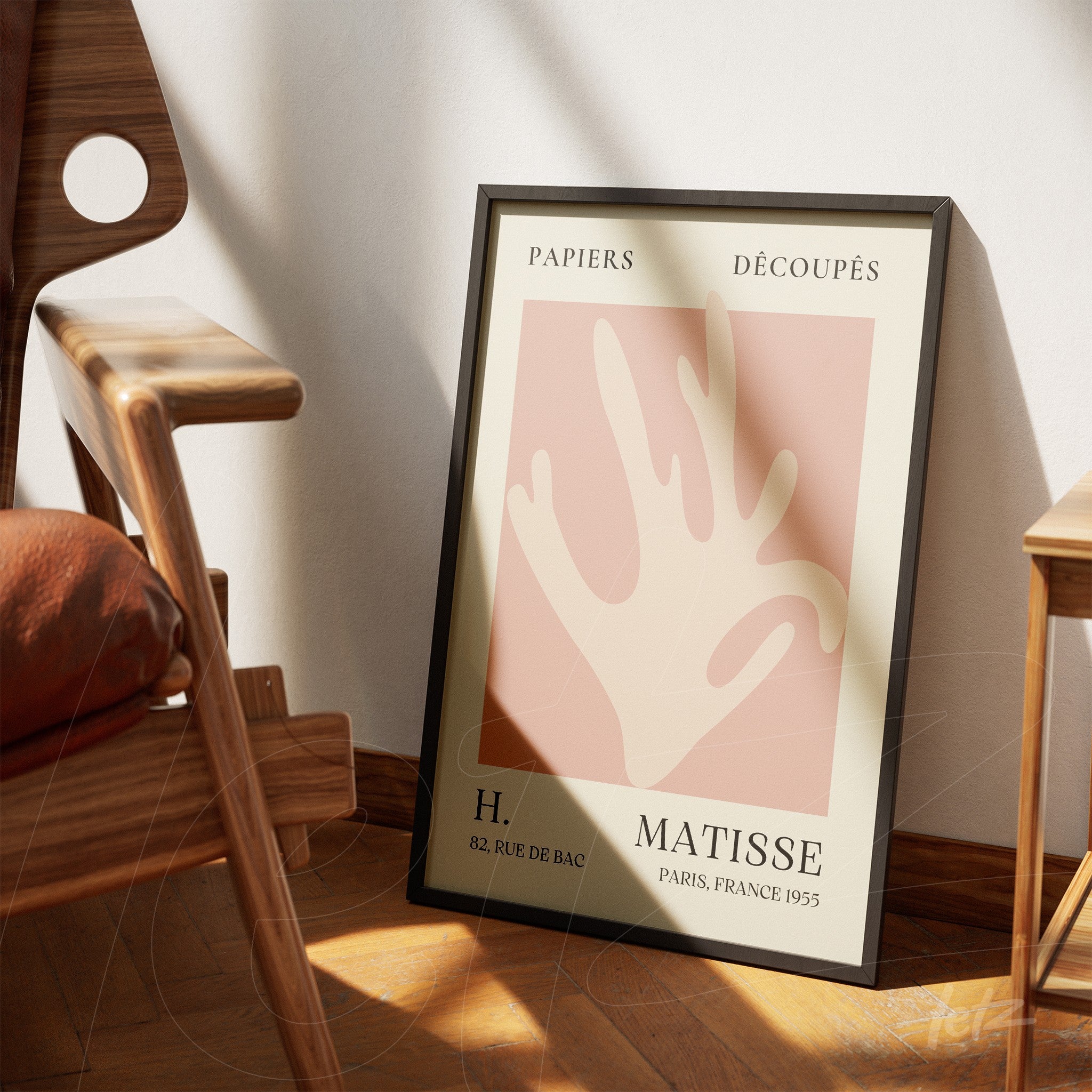 quadro com arte moderna em tons pastel, apresentando uma mão estilizada, moldura preta elegante, apoiado ao lado de uma cadeira de madeira