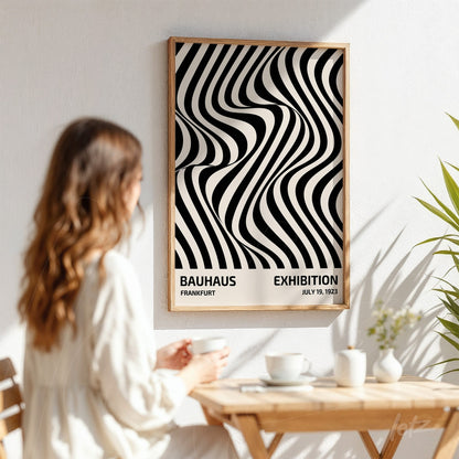 mulher observando pôster de arte abstrata em preto e branco com padrão ondulado, moldura de madeira clara e fundo de parede branca