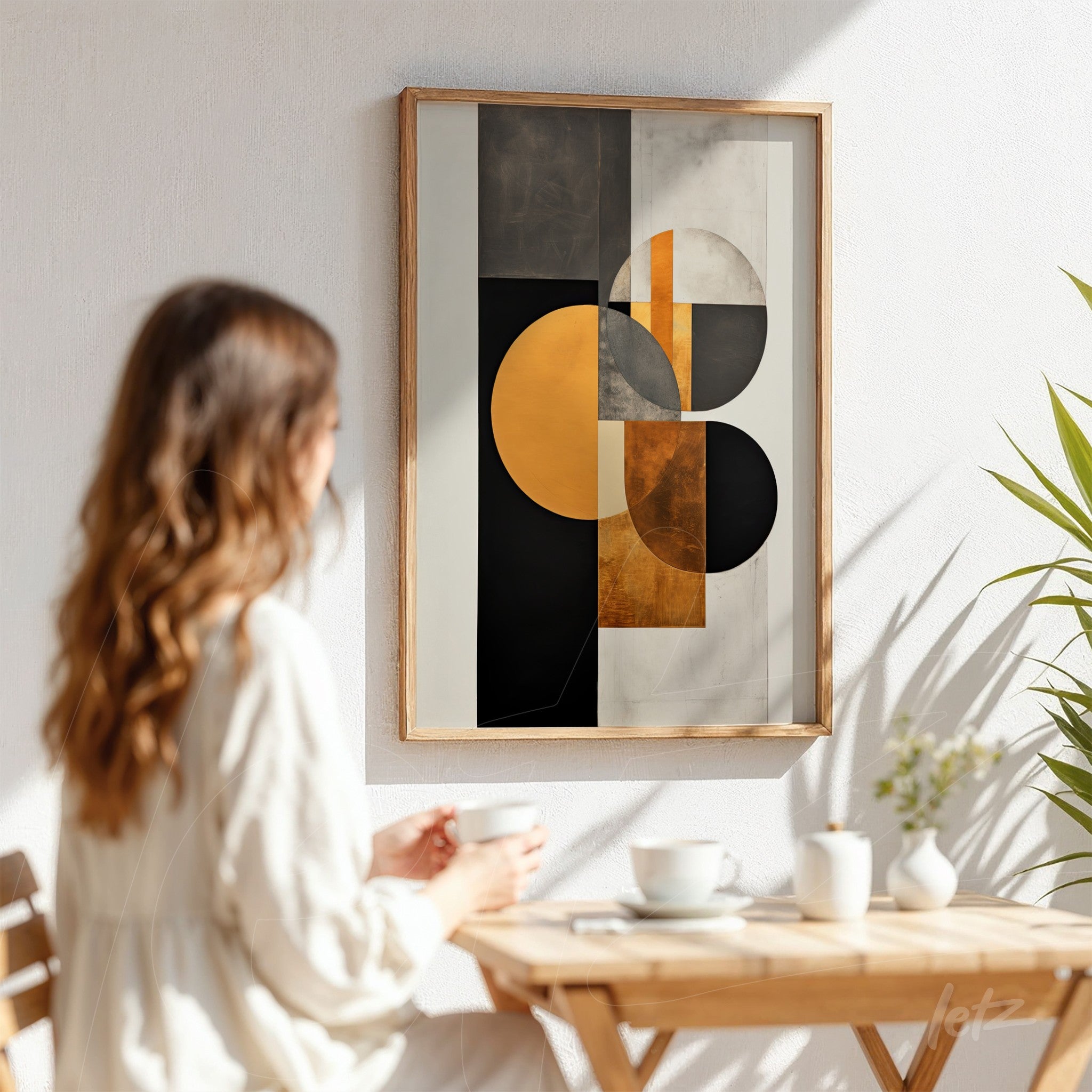 quadro abstrato em moldura de madeira clara com formas geométricas em preto, dourado e branco, exibido em ambiente iluminado