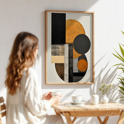 quadro abstrato com formas geométricas em tons de preto, laranja e cinza, em moldura de madeira clara, exibido na parede com iluminação natural