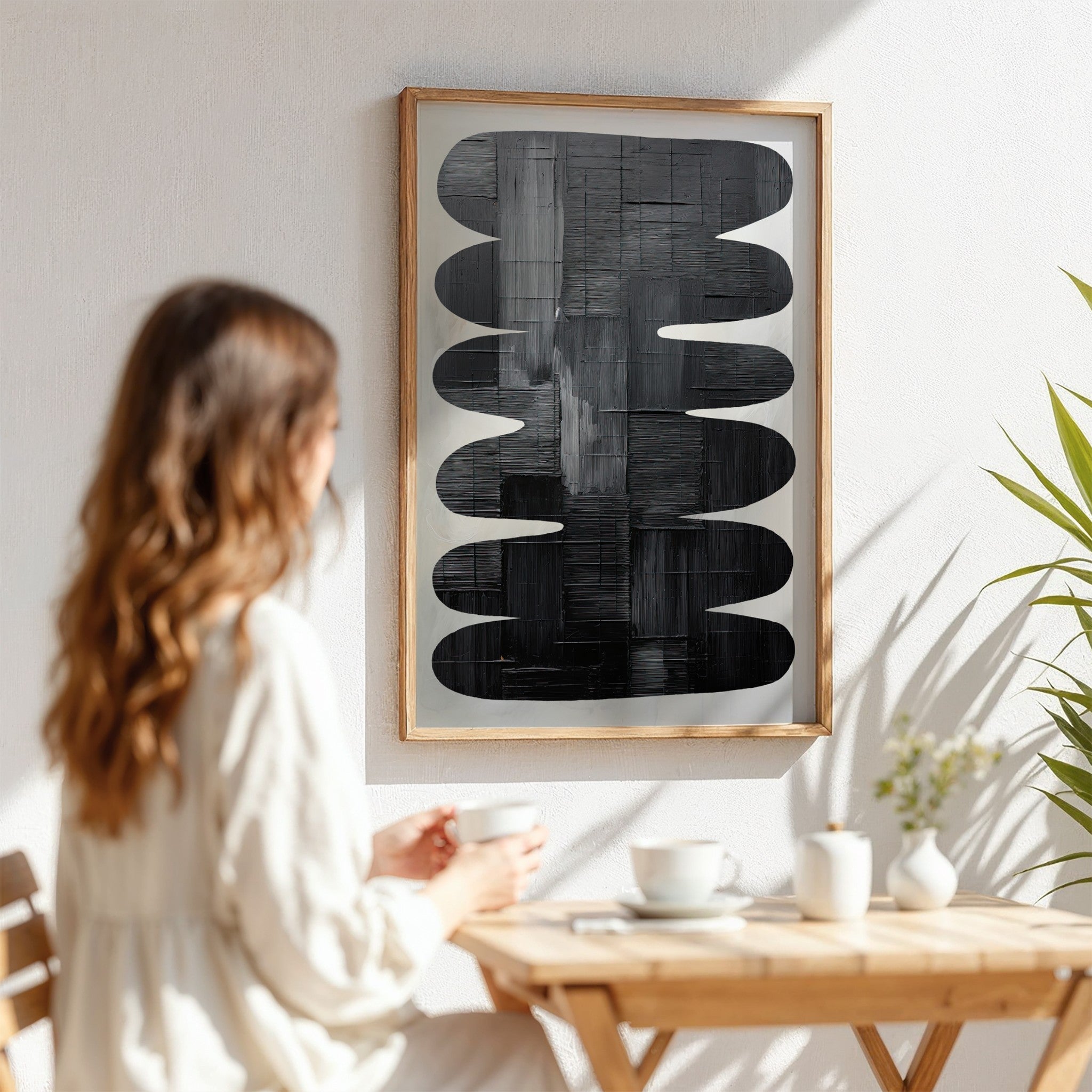 quadro com arte abstrata em preto e branco em moldura de madeira clara, exibido em parede iluminada pelo sol