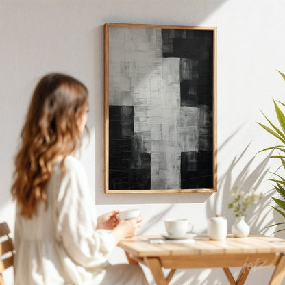 quadro abstrato em preto e branco com texturas variadas em moldura de madeira clara, exposto sobre parede branca