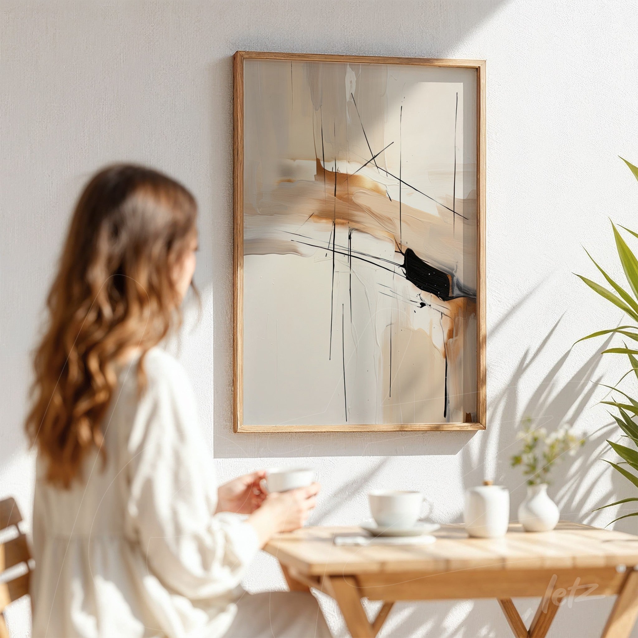 quadro abstrato em tons terrosos com traços pretos em moldura de madeira clara, pendurado em parede branca