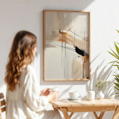 quadro abstrato em tons terrosos com traços pretos em moldura de madeira clara, pendurado em parede branca