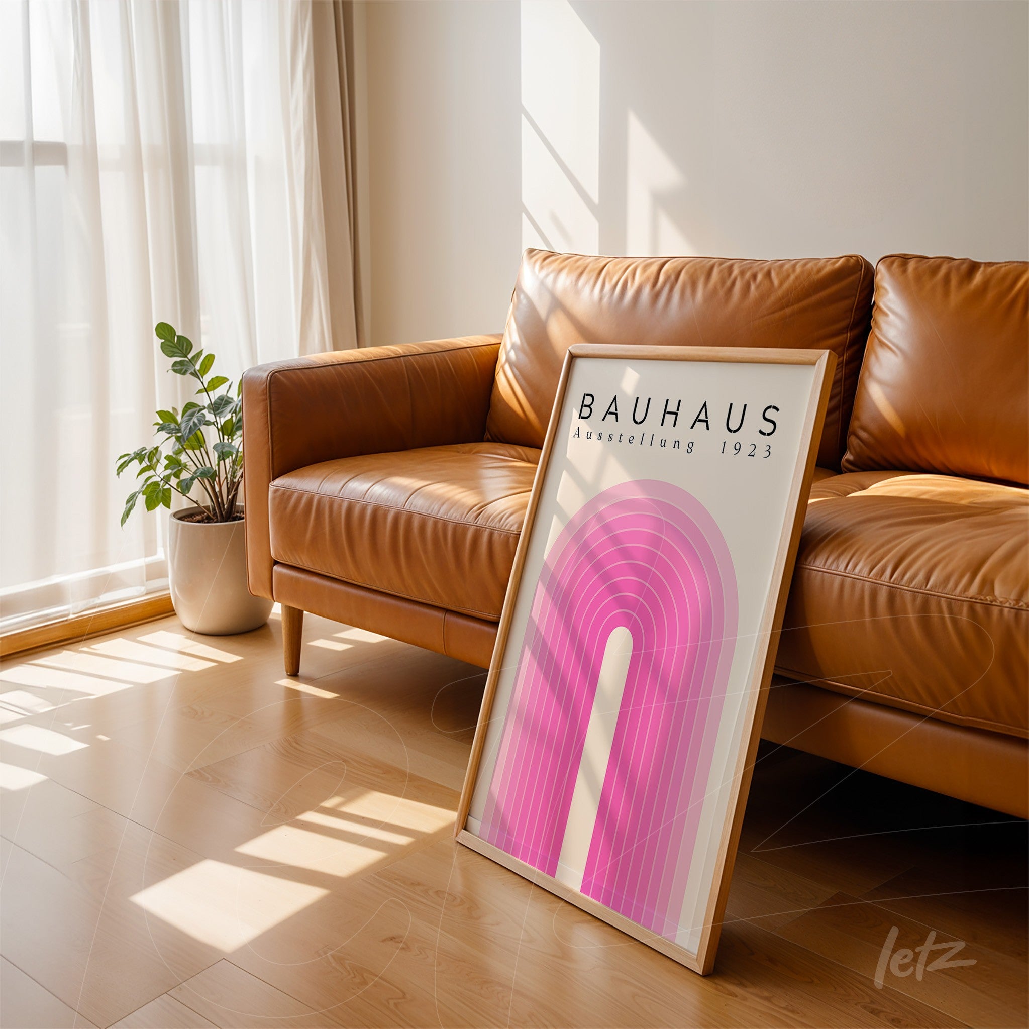 quadro em estilo bauhaus com formas geométricas rosa e moldura de madeira encostado em sofá de couro marrom