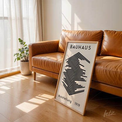 poster com arte geométrica em preto e branco estilo Bauhaus, encostado em sofá de couro marrom