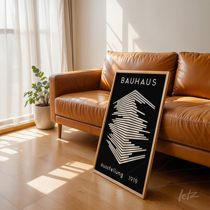 quadro com geometria minimalista em estilo Bauhaus encostado em sofá de couro marrom claro, emoldurado com madeira clara