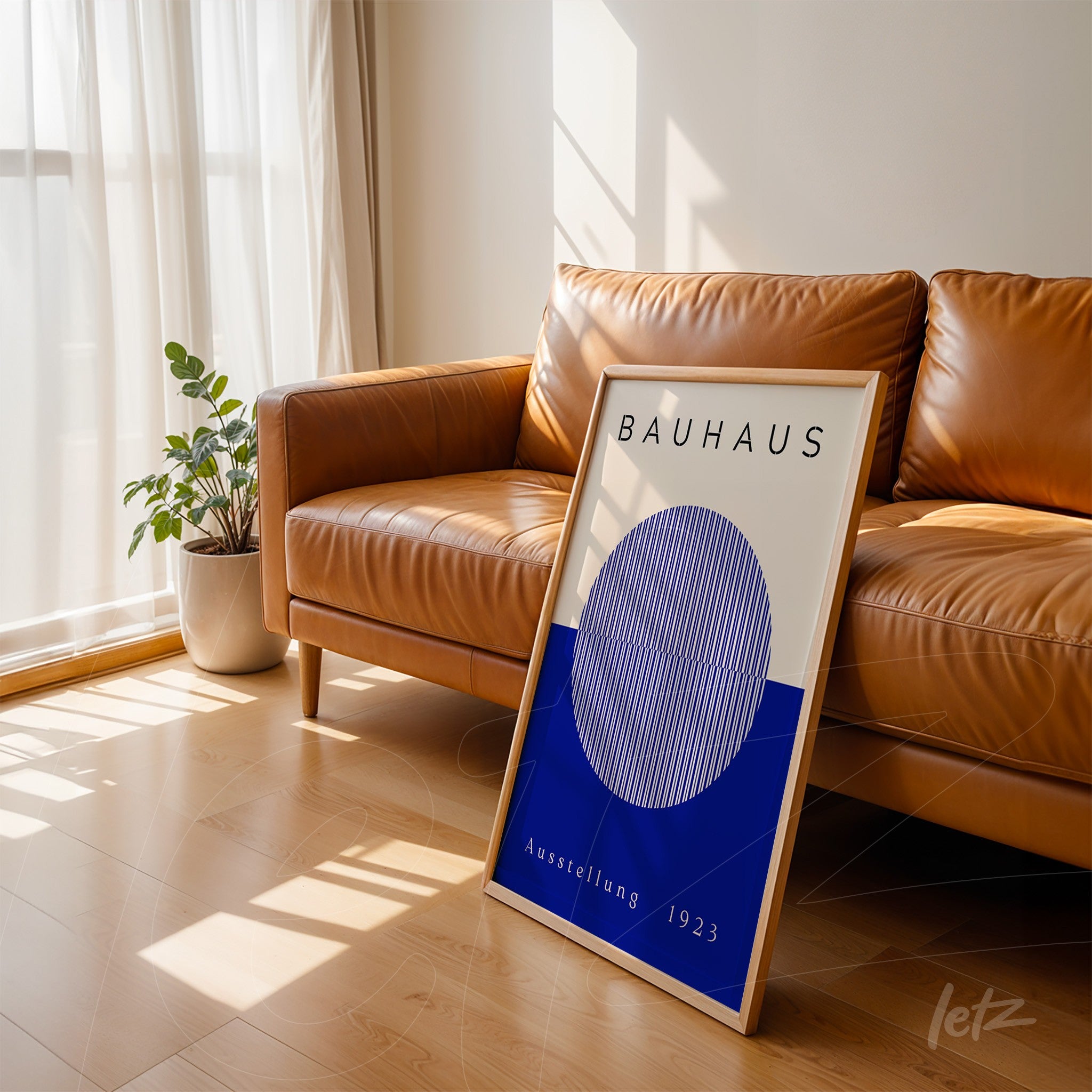 quadro decorativo estilo Bauhaus com moldura de madeira clara exibido apoiado em sofá de couro marrom em ambiente bem iluminado