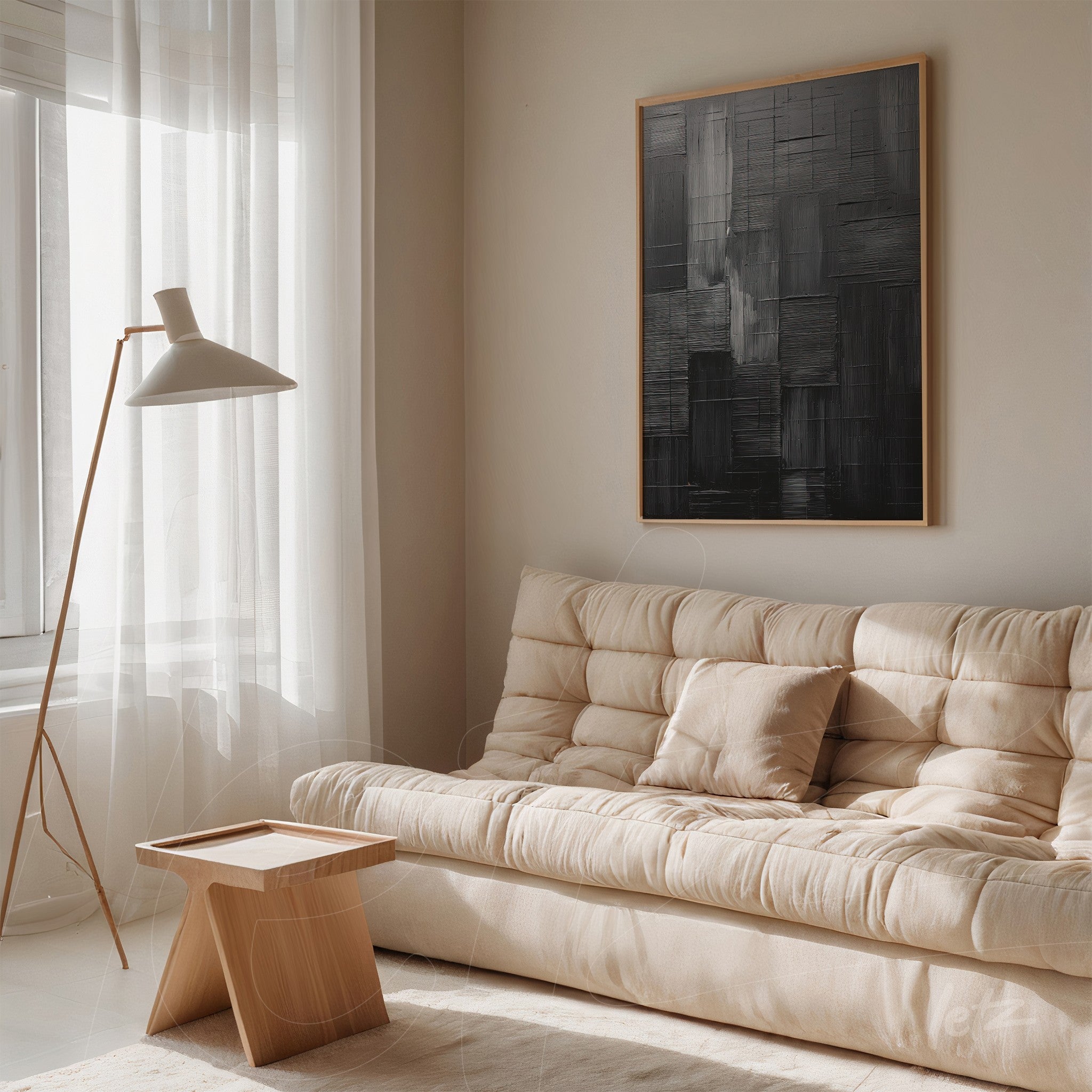 quadro abstrato em tons de preto e cinza com moldura clara, exibido em ambiente minimalista com sofá bege e luz natural