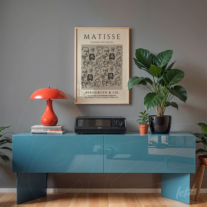 quadro com arte de Matisse em moldura bege sobre um móvel azul moderno, decorado com plantas e abajur laranja