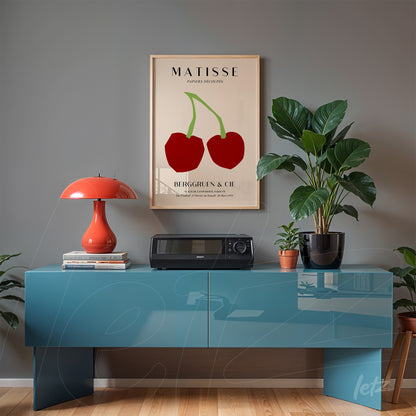 quadro em moldura bege com arte colorida de cerejas de Matisse, exposto sobre console azul sob parede cinza
