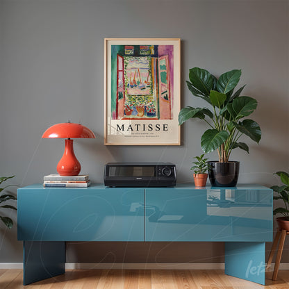 quadro vintage com arte de paisagem de Matisse em moldura clara sobre um aparador azul, decorado com lâmpada vermelha e plantas verdes