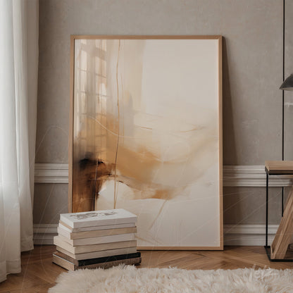 quadro abstrato com tons de beige e caramelo em moldura clara, apoiado ao lado de uma mesa de madeira