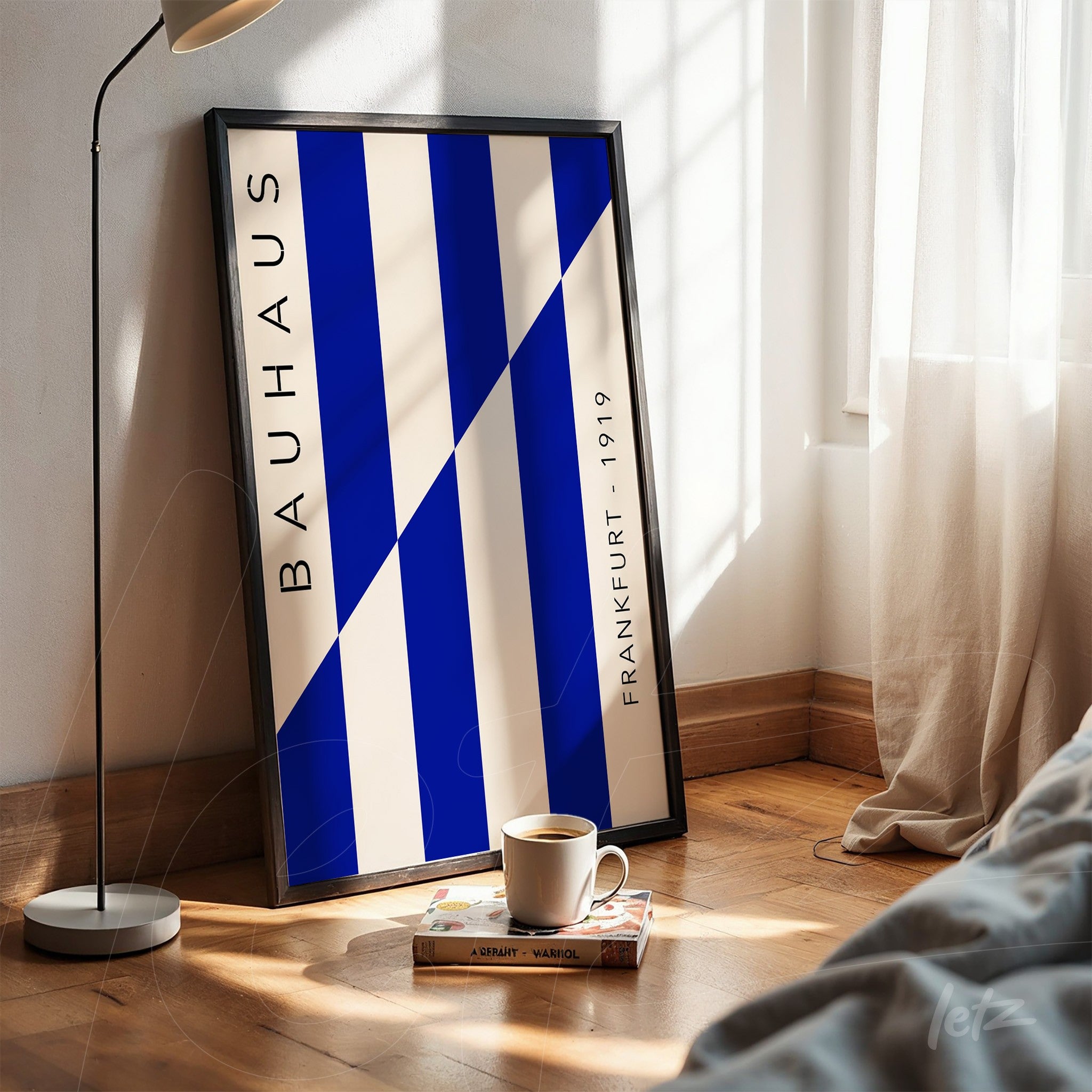 pôster com design estilo bauhaus em tons de azul e branco com moldura preta apoiado no chão de madeira
