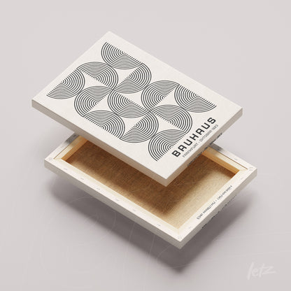 tela em canvas com arte geométrica em preto e branco de círculos concêntricos sobre fundo bege claro, exibida virada com a borda à mostra