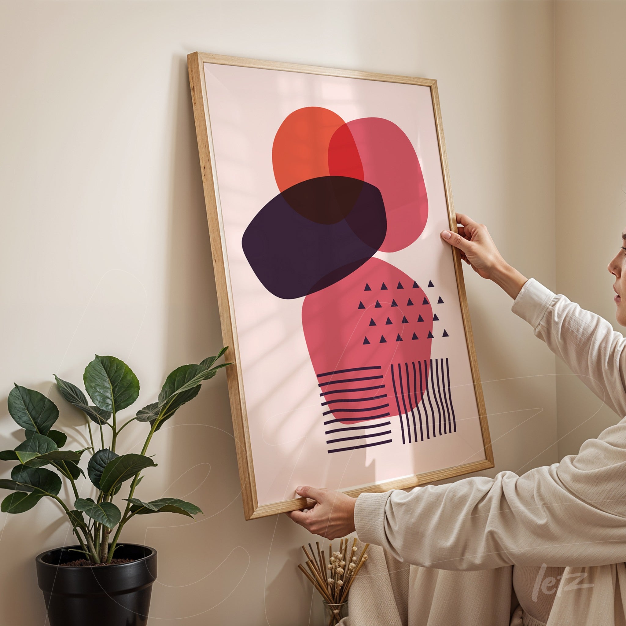 quadro com arte geométrica abstrata em tons de rosa e preto, exibido com moldura de madeira clara