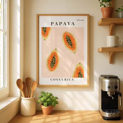 quadro com ilustração de papaias em fundo rosa com moldura de madeira clara, exibido em ambiente de cozinha iluminada