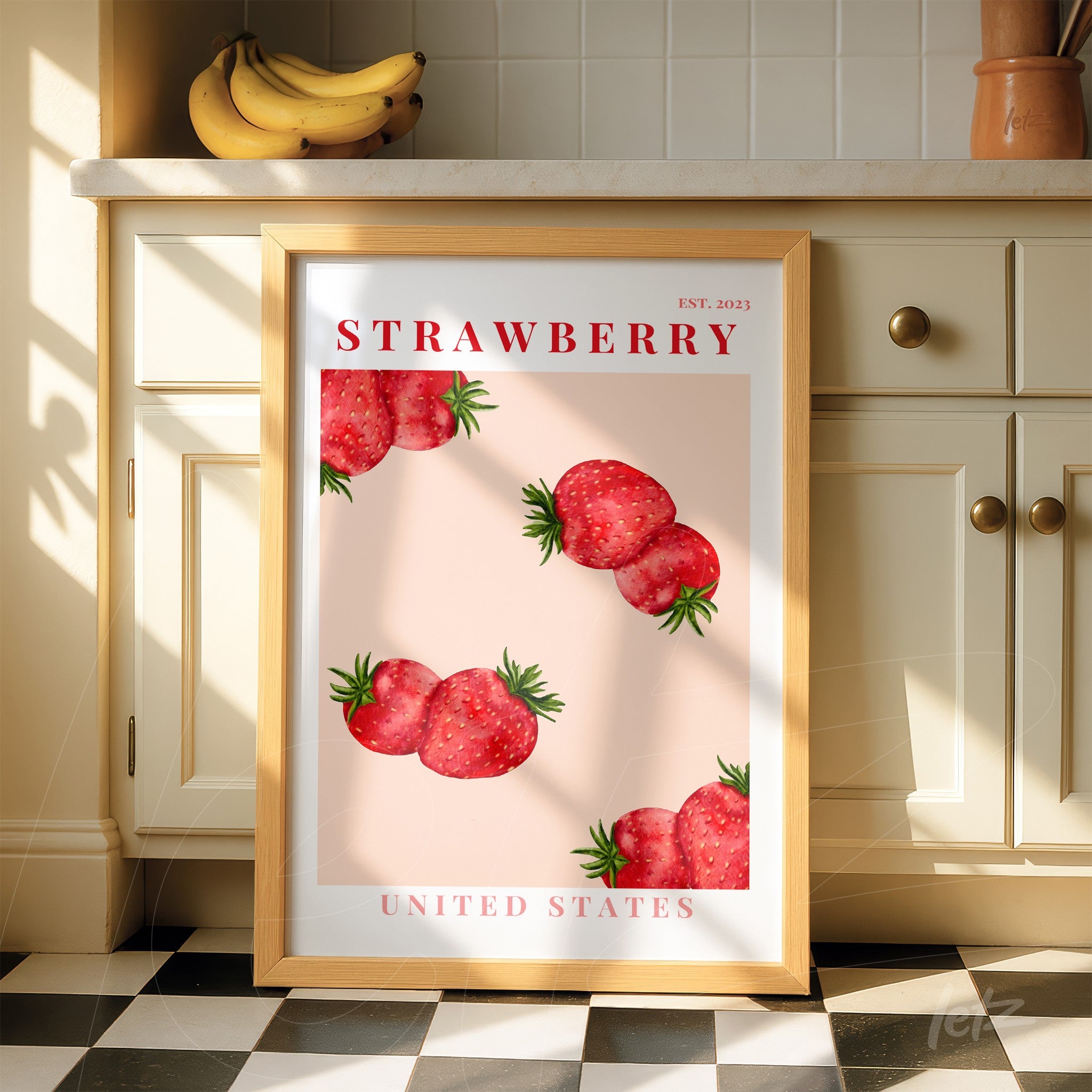 quadro decorativo com ilustração de morangos sobre fundo rosa, moldura de madeira clara e texto em vermelho