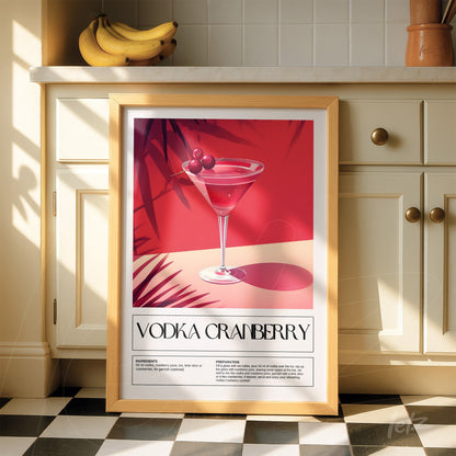 quadro emoldurado com arte retrô do drink vodka cranberry, apresentado com fundo vermelho e detalhes de folhas, apoiado sobre uma superfície de cozinha clara