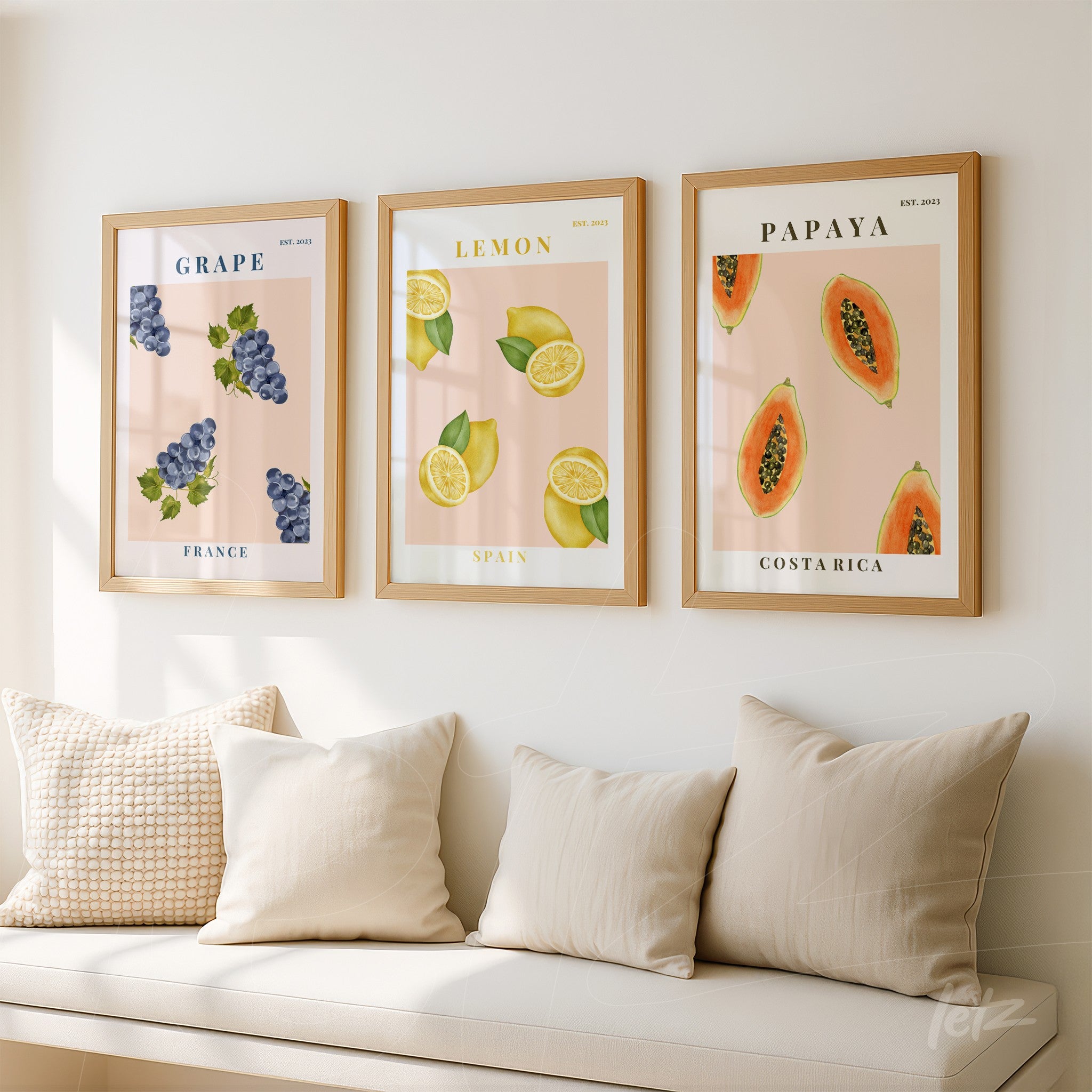 composição de quadros com ilustrações de uvas, limões e papaia em molduras de madeira clara, exibidos em uma parede branca com sofás claros ao fundo