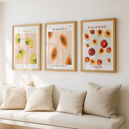 composição de quadros decorativos com frutas tropicais, incluindo limões, papaias e pêssegos, em molduras de madeira clara dispostos sobre uma parede clara