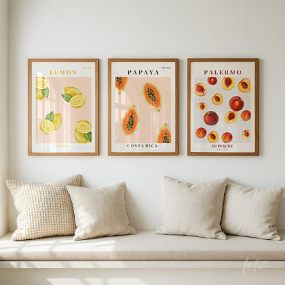 composição de três quadros decorativos com frutas sobre parede clara, incluindo limões, mamões e pêssegos, todos em molduras de madeira clara