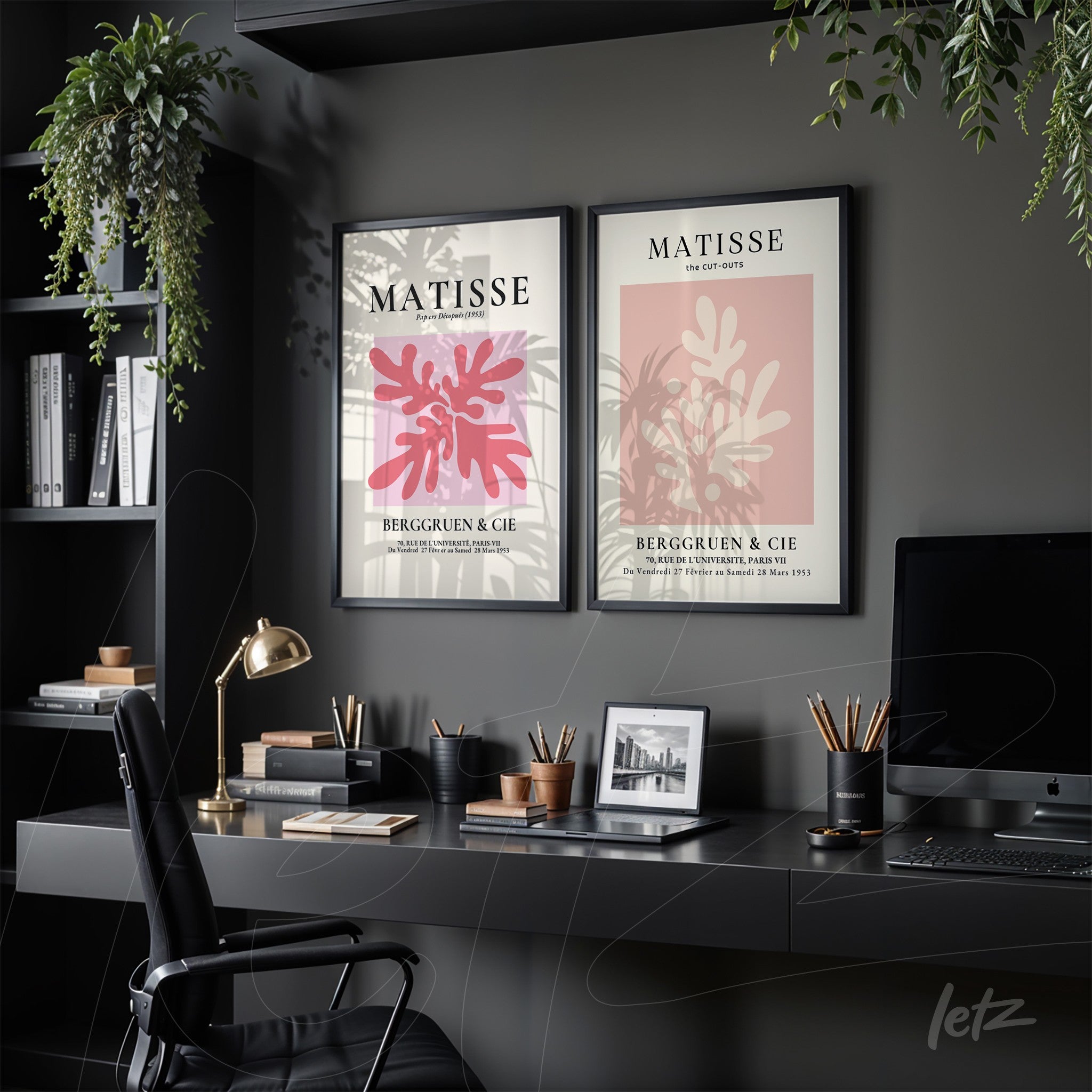 composição com dois quadros decorativos em moldura preta exibidos sobre uma mesa de trabalho, ambos com design inspirado em Matisse, um com folha rosa e o outro em fundo vermelho com plantas