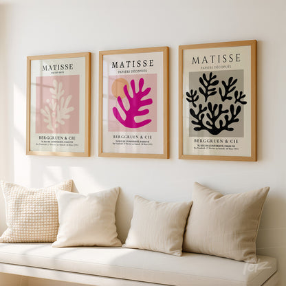 composição com três quadros decorativos de estilo moderno, molduras de madeira clara, arte em tons de rosa e preto com elementos botânicos