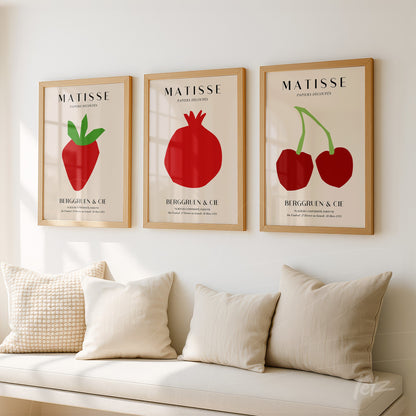 série de quadros decorativos com ilustrações de frutas vermelhas em molduras de madeira clara sobre parede neutra