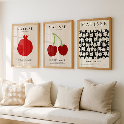 composição com três quadros decorativos em moldura de madeira clara exibindo arte inspirada em Matisse com elementos como romã, cerejas e flores brancas sobre fundo negro