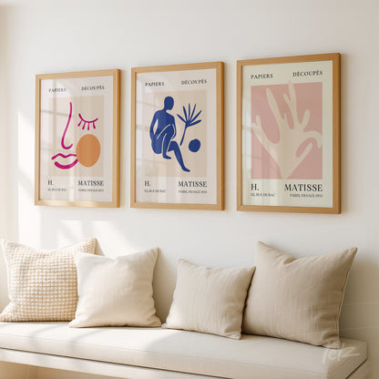 composição de três quadros decorativos em moldura de madeira clara com arte abstrata em tons suaves e figuras estilizadas