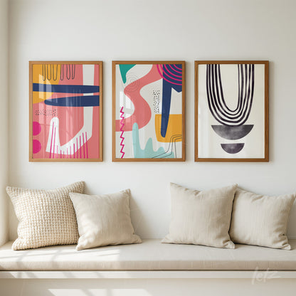 composição com três quadros em estilo boho com cores modernas, exibidos em molduras de madeira sobre uma parede branca acima de um assento com almofadas bege