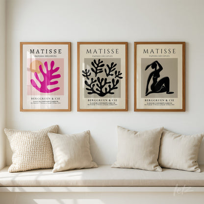 composição de três quadros com arte em estilo cut-out de Matisse em moldura de madeira clara sobre sofá neutro