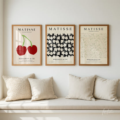 composição de três quadros com arte inspirada em Matisse, incluindo cerejas vermelhas, flores brancas sobre fundo preto e padrão floral verde claro em moldura de madeira clara